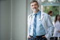 Confident smiling doctor posing in the hospital with medical team working on the background.