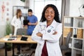 Afro-American doctor posing with arms crossed and diverse medical team working on the background Royalty Free Stock Photo