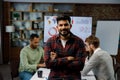 Confident smiling Indian guy, startup team leader, standing in front of mixed race office workers or business people Royalty Free Stock Photo