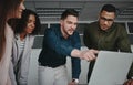 Confident smiling male executive manager explains to his colleagues new online project startup on laptop in the office Royalty Free Stock Photo