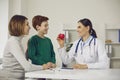 Confident smiling woman pediatrician showing happy heart to positive boy teen patient and his mother Royalty Free Stock Photo