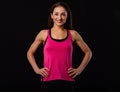 Confident sportswoman in pink sportsbra and shirt, holding hands on waist, fitness trainer standing in power pose, workout in gym