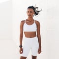 Confident sportswoman in white fitness clothes standing outdoors