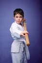 Confident strong concentrated boy - Aikido wrestler - in a kimono stands with a wooden jo weapon in his hands. Oriental martial