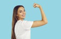 Confident strong happy woman smiling and showing her power flexing arm on blue background. Royalty Free Stock Photo