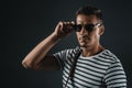 confident stylish man posing in striped t-shirt and sunglasses