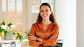 Confident stylish woman laughing with arms crossed and standing inside a modern office near a window. Face portrait of a Royalty Free Stock Photo