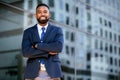 Confident successful african american businessman standing with arms folded, smiling, downtown financial district Royalty Free Stock Photo
