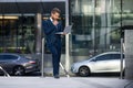 Confident and successful businessman talking on the phone holding a laptop. Brainstorm concept. Royalty Free Stock Photo