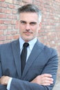 Confident and successful. Cheerful mature man in suit, shirt and tie looking at camera and keeping arms crossed while standing Royalty Free Stock Photo