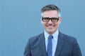 Confident and successful. Cheerful mature man in suit, shirt and tie looking at camera while standing against blue background Royalty Free Stock Photo