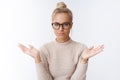 Confident successful european blond woman in glasses with bun haircut spread hands unaware and unbothered feeling Royalty Free Stock Photo