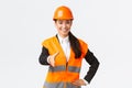 Confident successful female architect, leader of construction in safety helmet, reflective jacket, extand hand for Royalty Free Stock Photo