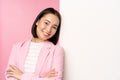 Confident, successful japanese office lady in suit, cross arms, looking as professional at camera, leaning on white wall Royalty Free Stock Photo