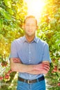 Confident supervisor standing with arms crossed in greehouse ang yellow lens flare