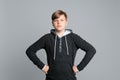 Confident teenage boy in hoodie posing over gray background Royalty Free Stock Photo