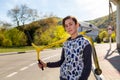 A confident teenage boy posing with a scooter in hand. In the background, a street and a road on a Sunny day. Concept of sports Royalty Free Stock Photo