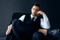 Confident thoughtful man in elegant suit posing sitting in chair