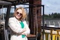 A confident trending middle-aged woman in a suit, holding her hands together, against the background of city Royalty Free Stock Photo