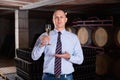 Confident winemaker offering glass of white sparkling wine for tasting in wine cellar Royalty Free Stock Photo