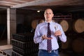 Confident winemaker offering glass of white sparkling wine for tasting in wine cellar Royalty Free Stock Photo