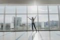 Confident woman spreading hands standing at office window, enjoying big city, successful entrepreneur celebrating business success