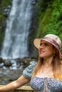 a woman is standing by a waterfall and looking over her shoulder Royalty Free Stock Photo