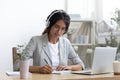 Confident woman student studying online in earphones by pc screen