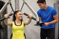 Confident woman using weights machine with trainer