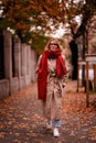 Confident woman wearing scarf and trench coat while walking alone on street Royalty Free Stock Photo