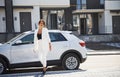 Confident woman in white formal wear outdoots near her white car Royalty Free Stock Photo