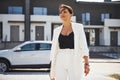 Confident woman in white formal wear outdoots near her white car Royalty Free Stock Photo