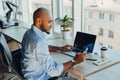 Have a nice working day. Confident young african american businessman working on laptop and talking on cell phone while sitting at Royalty Free Stock Photo