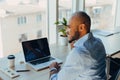 Have a nice working day. Confident young african american businessman working on laptop and talking on cell phone while sitting at Royalty Free Stock Photo