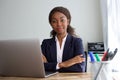 Confident young african american businesswoman in suit sitting at office desk Royalty Free Stock Photo