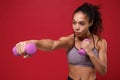 Confident young african american sports fitness woman in sportswear working out isolated on red background in studio Royalty Free Stock Photo