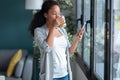 Confident young african american woman using her mobile phone while sitting on sofa at home Royalty Free Stock Photo