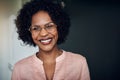 Confident young African businesswoman standing in an office laughing