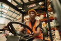 Young African female forklift operator driving around a warehouse Royalty Free Stock Photo