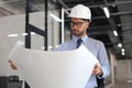 Confident young architect in hardhat holding a blueprint and looking at area for work Royalty Free Stock Photo