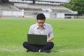 Confident young Asian business man in formal wear using laptop for his job at the field Royalty Free Stock Photo
