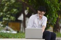 Confident young Asian business man in formal wear using laptop for his job at the park during morning time Royalty Free Stock Photo