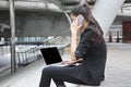 Confident young Asian business woman using laptop and mobile smart phone for job at outside office Royalty Free Stock Photo