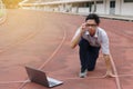 Confident young Asian businessman with laptop ready start position to forward on race track with sunshine effect. Competition and Royalty Free Stock Photo