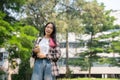 A confident young Asian female college student is looking at the camera while standing in the park Royalty Free Stock Photo