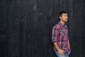 Confident young Asian man leaning against a dark wall outside Royalty Free Stock Photo