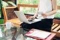 Confident young asian woman in smart casual wear working on laptop while sitting near window in creative office or cafe Royalty Free Stock Photo