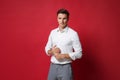 Confident young business man in white shirt, gray pants posing isolated on bright red wall background studio portrait Royalty Free Stock Photo