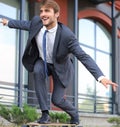 Confident young businessman in business suit on longboard hurrying to his office, on the street in the city