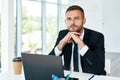 Confident young businessman in elegant suit posing in a bright modern office. sitting at his desk Royalty Free Stock Photo